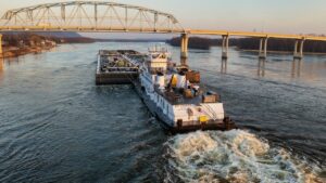 Simulatie binnenvaartopleiding: een binnenvaartschip manoeuvreert onder een brug bij daglicht