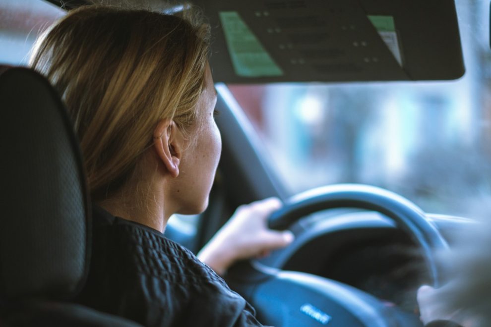 Jonge bestuurster kijkt geconcentreerd vooruit tijdens het autorijden