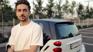 Jonge bestuurder staat naast geparkeerde auto op lege parkeerplaats