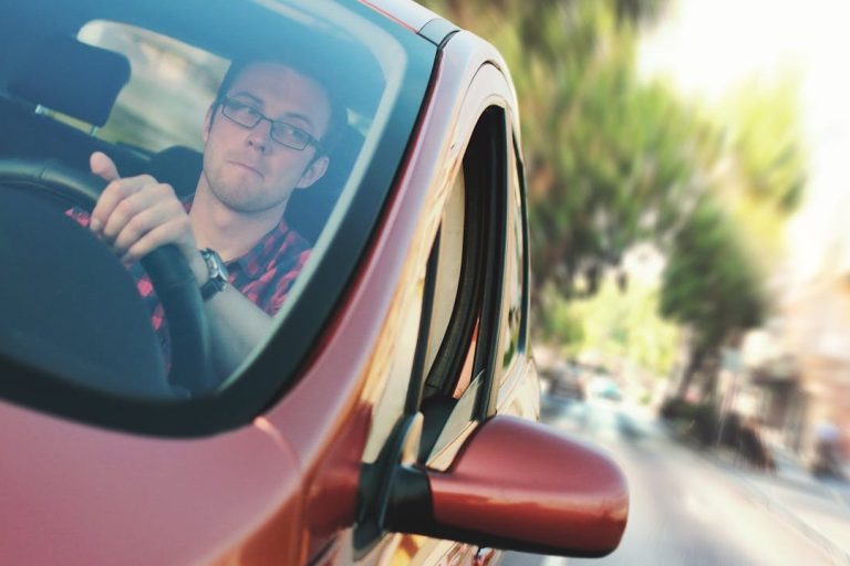 Man bestuurt moderne lesauto door stadsverkeer met focus op de weg