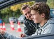 Jonge bestuurder krijgt uitleg van instructeur tijdens praktijkles over het aantal rijlessen.