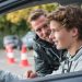 Jonge bestuurder krijgt uitleg van instructeur tijdens praktijkles over het aantal rijlessen.