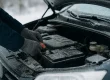 Handen controleren autobatterij om autopech voorkomen in winter