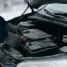 Handen controleren autobatterij om autopech voorkomen in winter